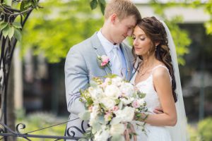 Portrait of a wedding couple embracing in front of a fence.