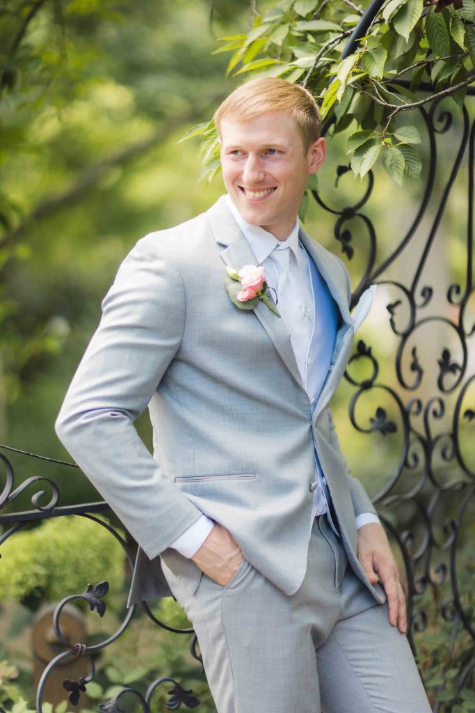 A man in a gray suit is posing for a wedding portrait.