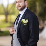 A groom in a tuxedo posing for a wedding portrait.