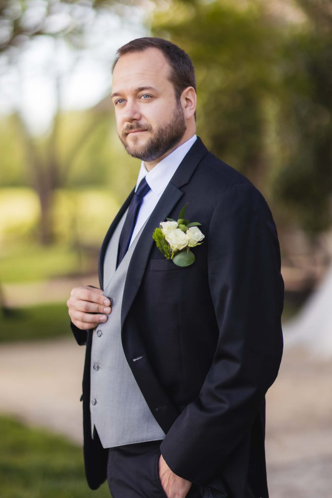 A groom in a tuxedo posing for a wedding portrait.