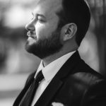A black and white wedding portrait of a groom in a suit.