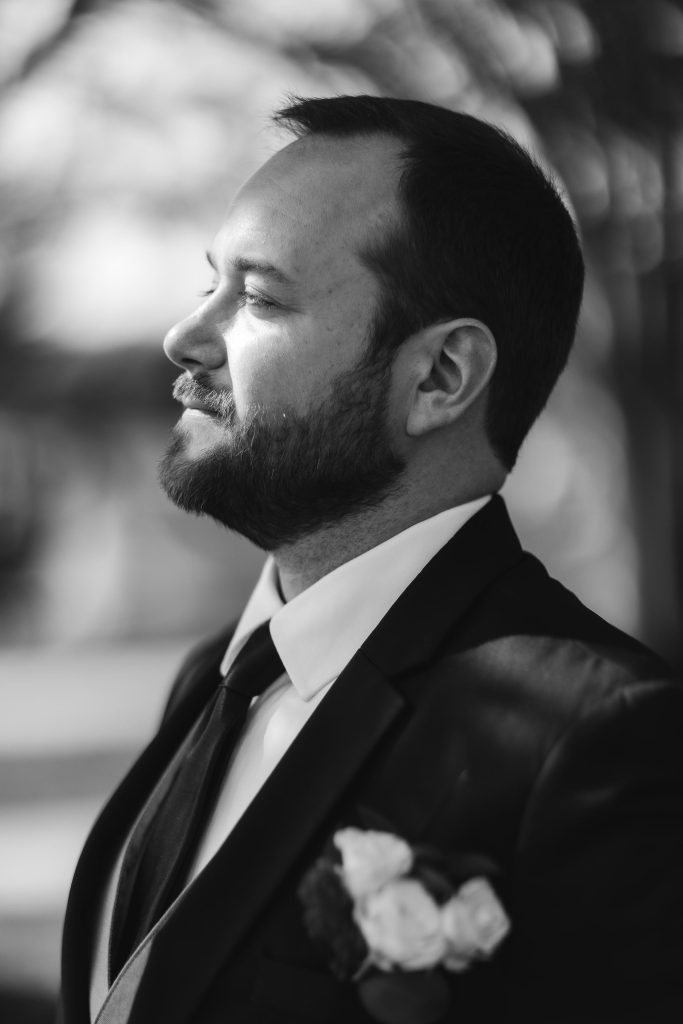 A black and white wedding portrait of a groom in a suit.