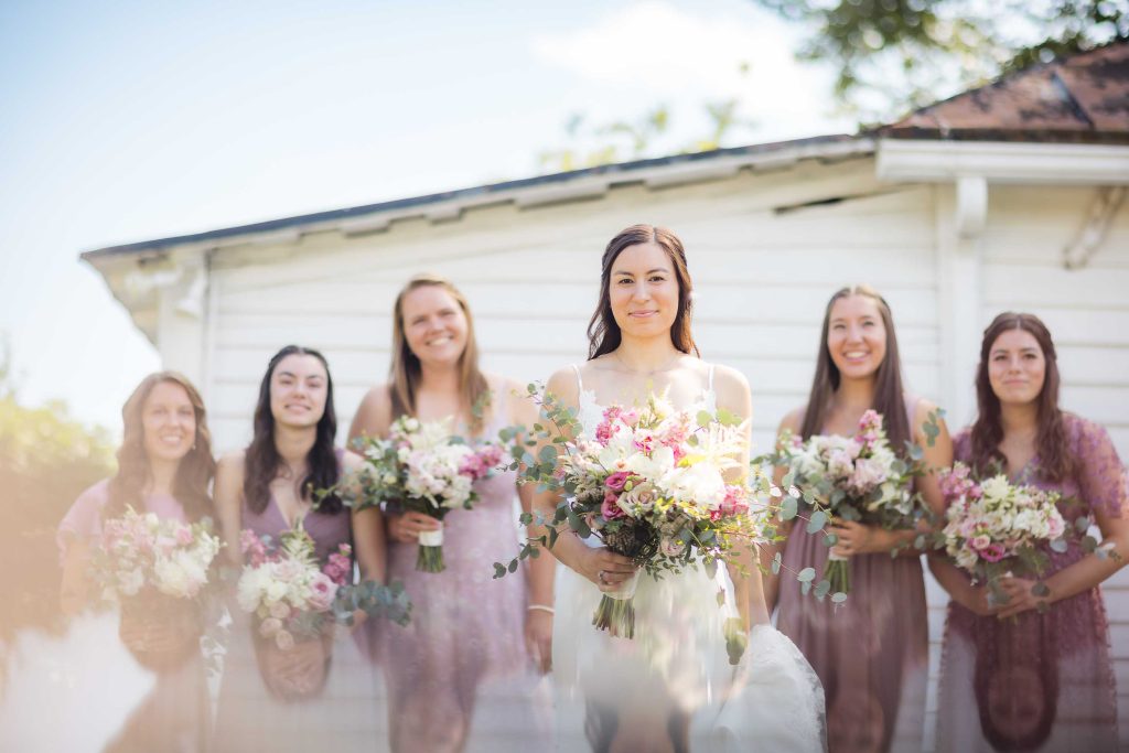 A group of bridesmaids posing for a wedding portrait in front of a house.