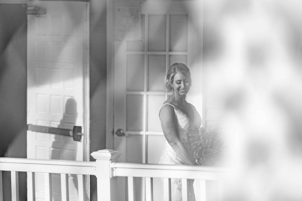 A black and white photo of a bride during her wedding ceremony on a porch.