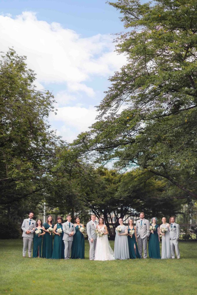 A group of wedding party members posing in front of a tree.