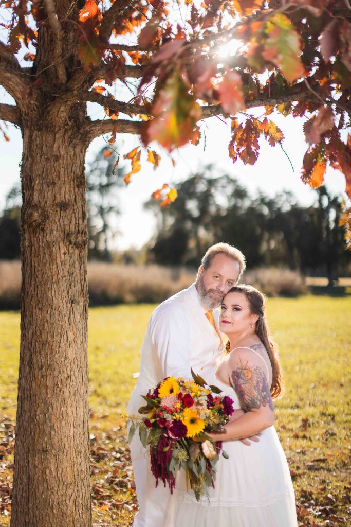 A couple posing under a tree at their wedding.
