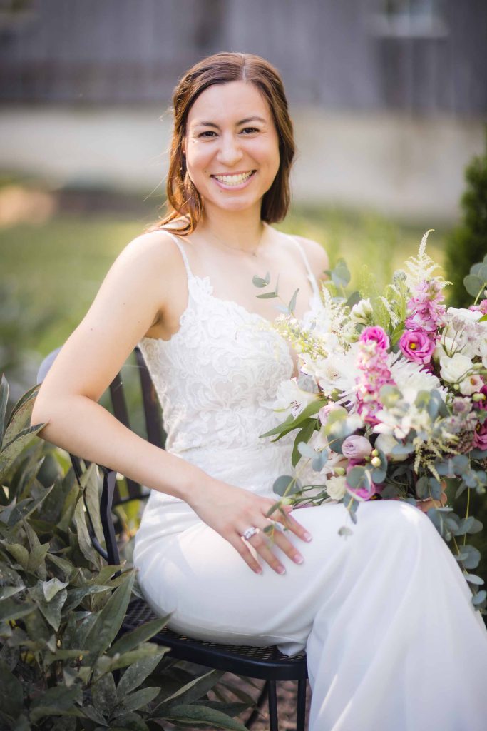 A bride sitting on a bench holding a bouquet for her wedding day portrait.