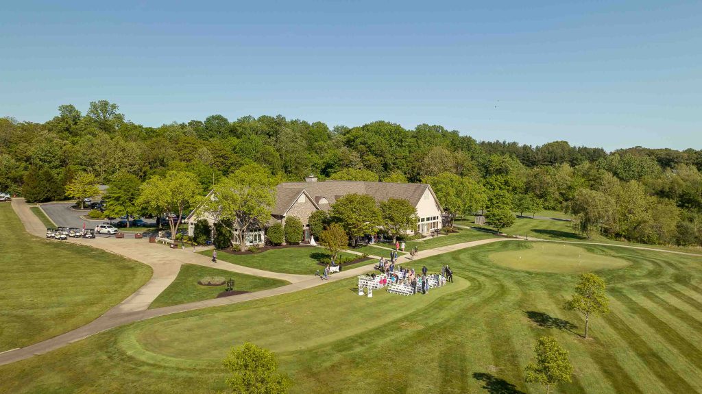 An aerial view of a golf course with a house in the background suitable for a wedding ceremony.