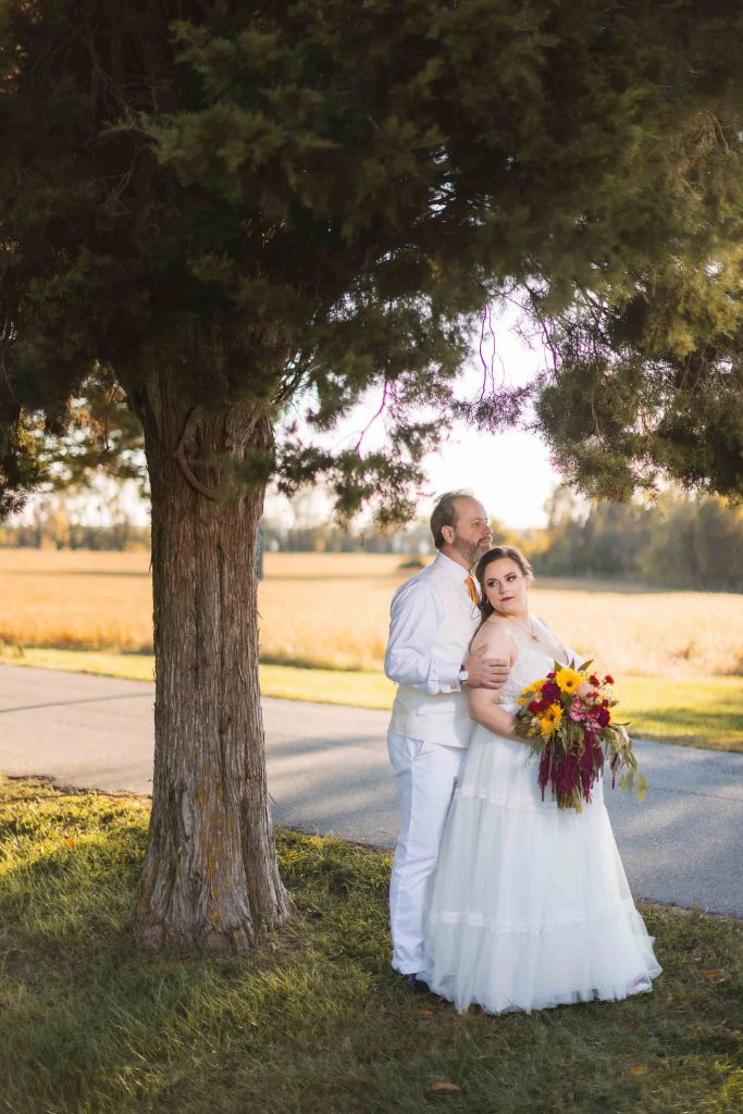 A wedding couple posing under a tree.