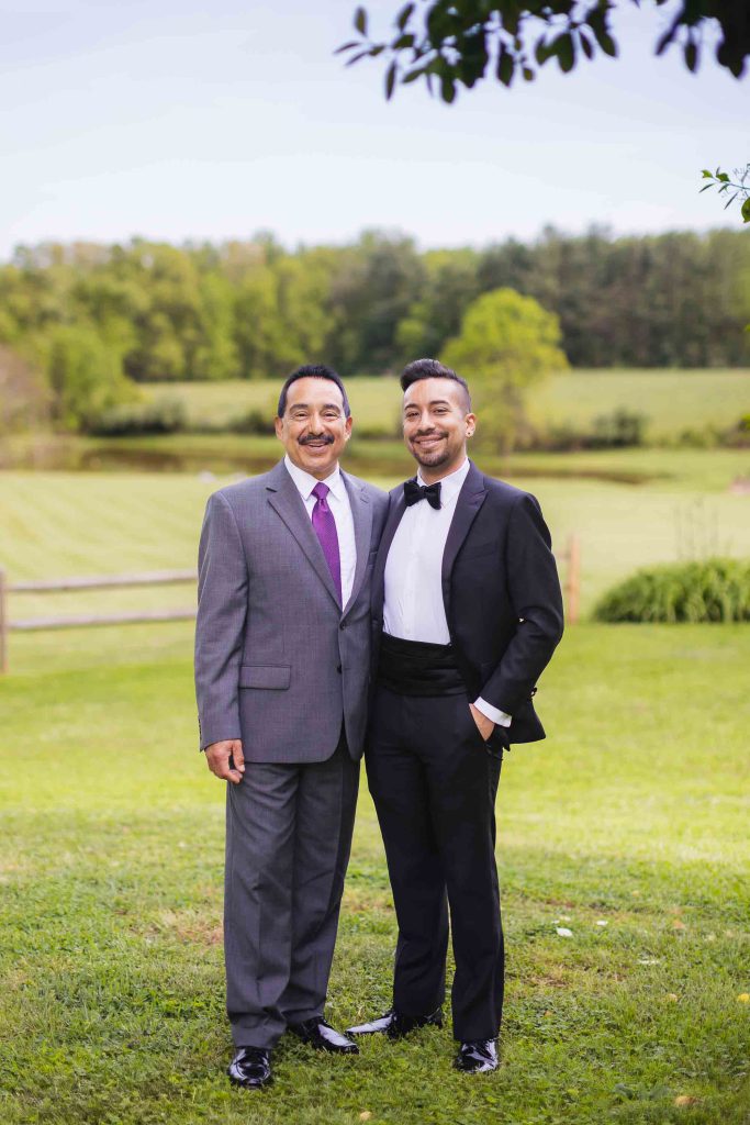 Two men in tuxedos posing for a wedding portrait.