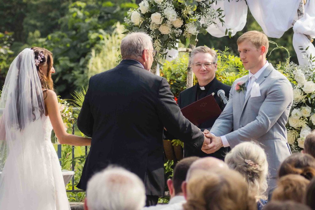A couple exchanges vows during their outdoor wedding ceremony.