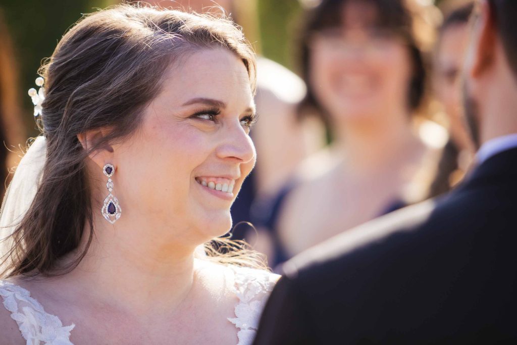 A couple smiles at each other during their wedding ceremony.