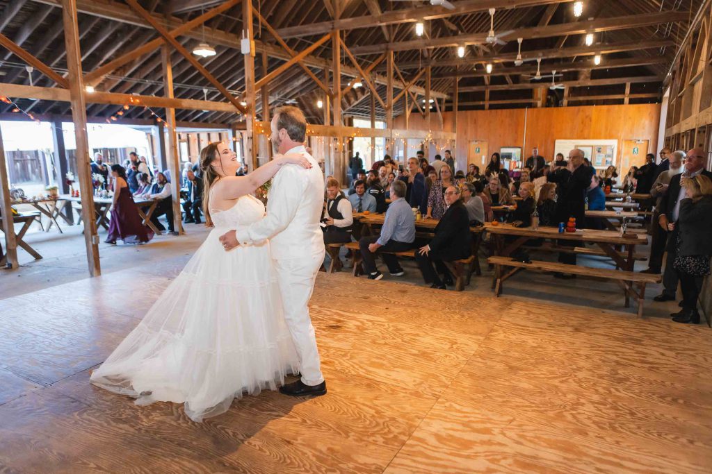 A bride and groom share their first dance at their wedding reception in a barn.