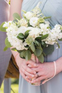 A bridesmaid gracefully holds a bouquet of white flowers, adding delicate details to the wedding.
