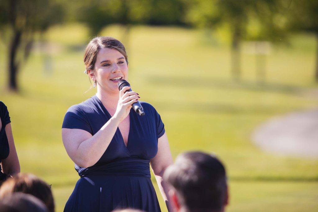 A woman is speaking into a microphone during a wedding ceremony.