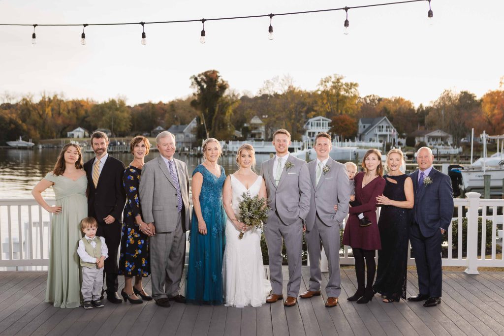 A wedding party posing for a portrait on a dock.