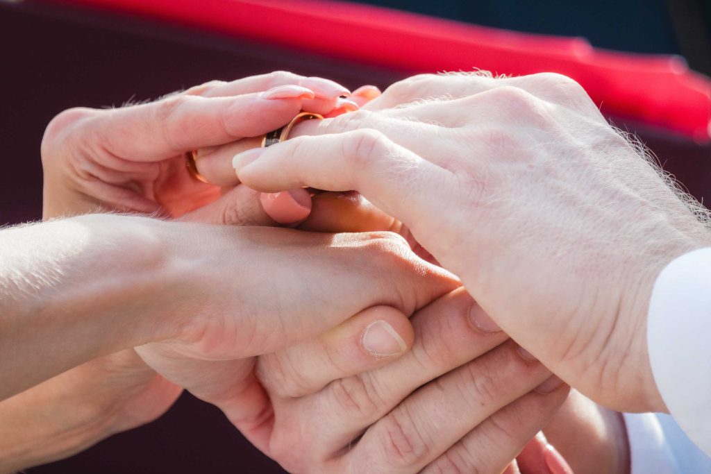 A man and woman participating in a wedding ceremony by exchanging rings.