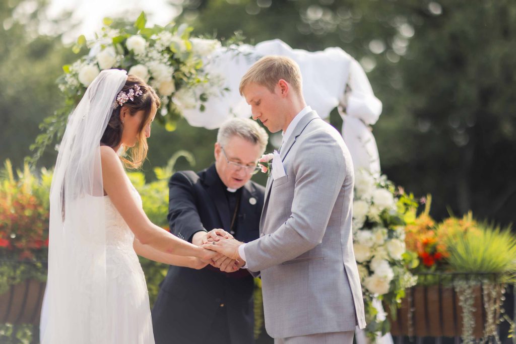 At a wedding ceremony, a bride and groom exchange rings.