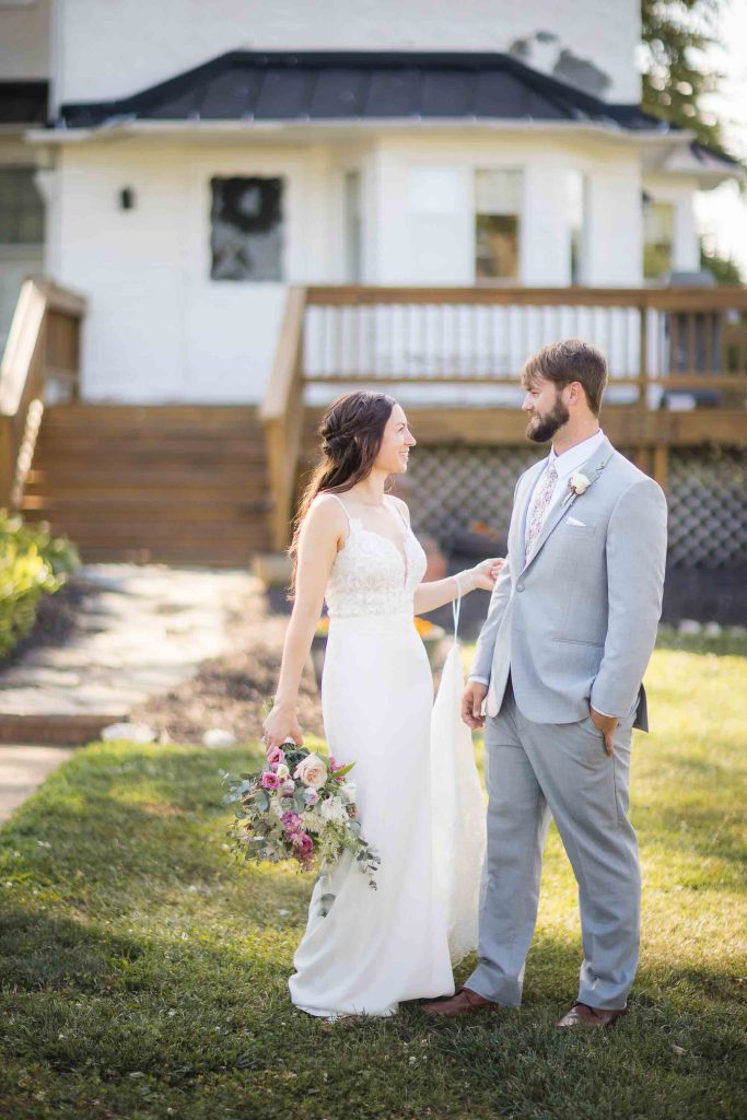 A wedding portrait of a bride and groom standing in front of a house.