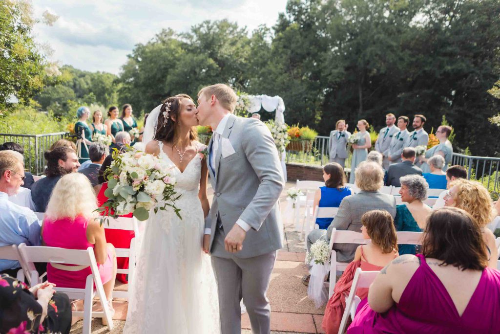 A couple shares a kiss during their outdoor wedding ceremony.