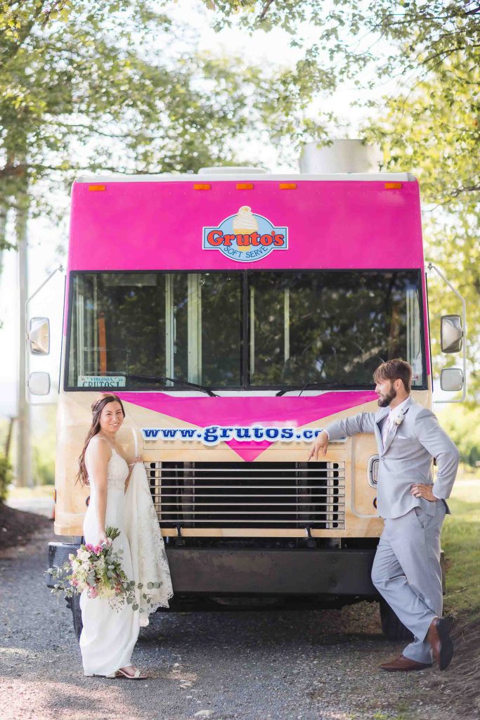 A wedding portrait next to a pink food truck.