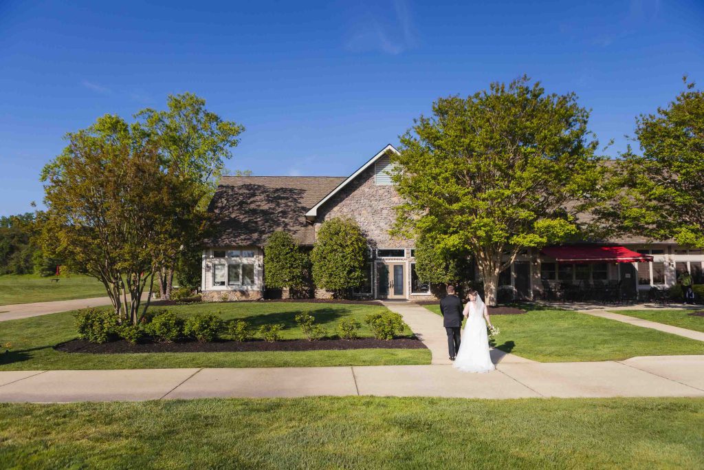A bride and groom standing in front of a house during their wedding ceremony.