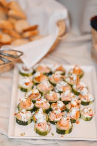 Salmon and cucumber appetizers elegantly displayed on a white plate for a wedding's meticulous details.