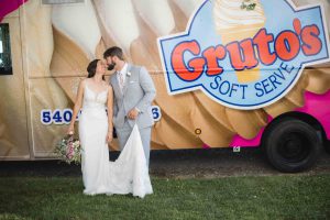 A bride and groom pose for a wedding portrait in front of a gruto's ice cream truck.