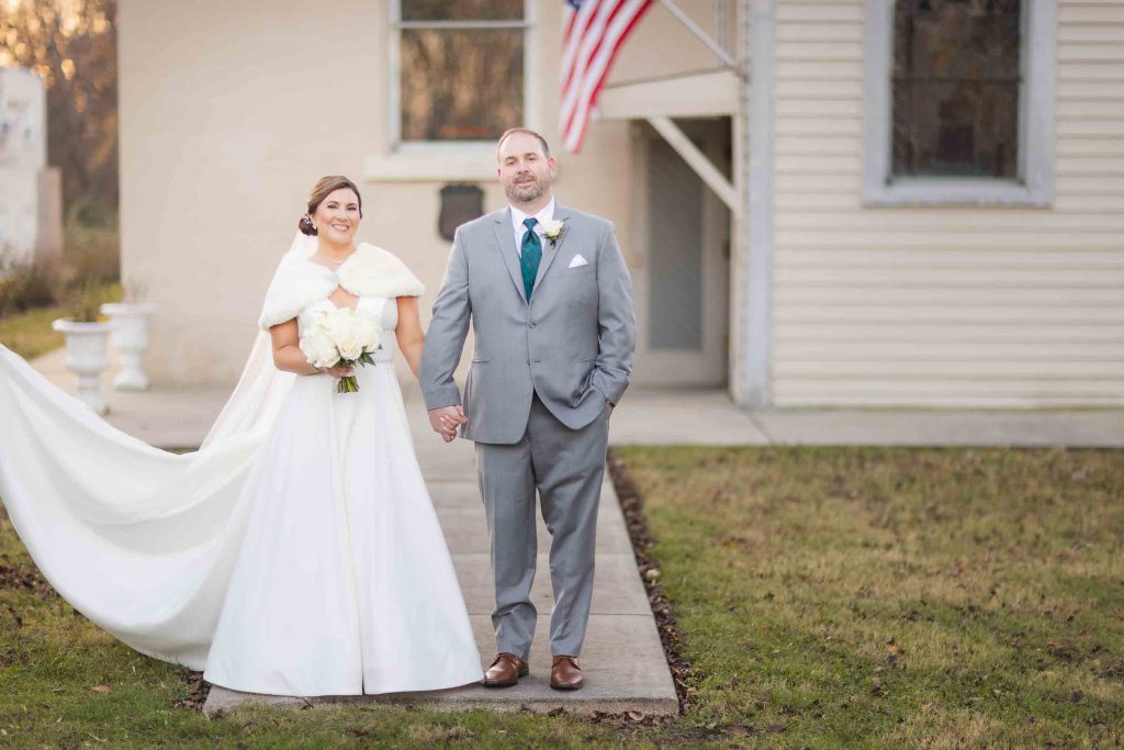A portrait of a bride and groom in front of a house.