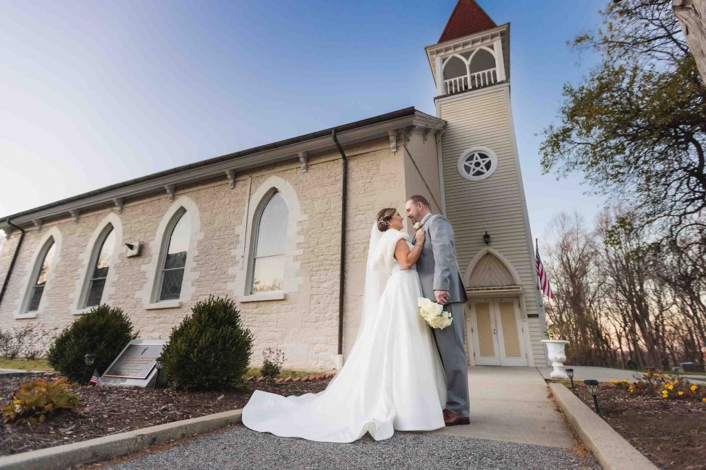 A wedding couple kiss in front of a church.