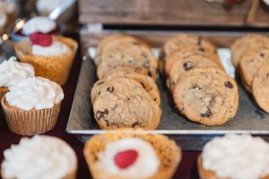 A tray of wedding cookies and cupcakes on a table.