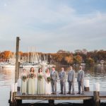 A portrait of a wedding party standing on a dock.