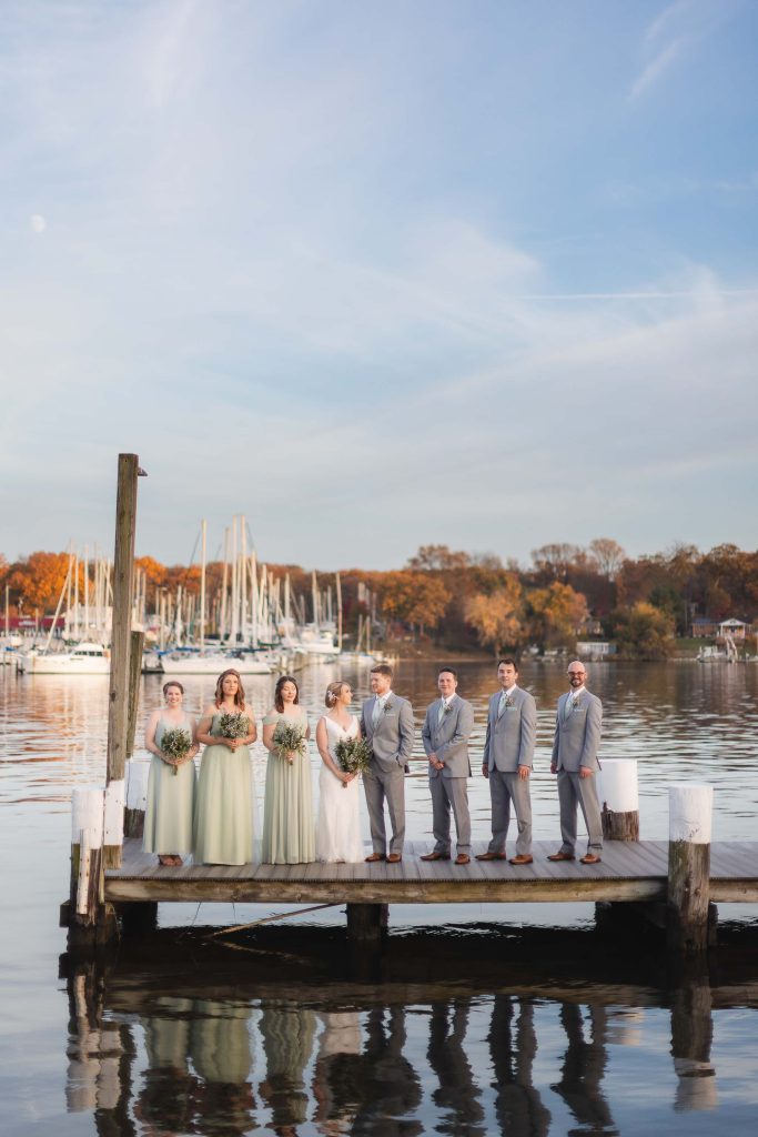 A portrait of a wedding party standing on a dock.