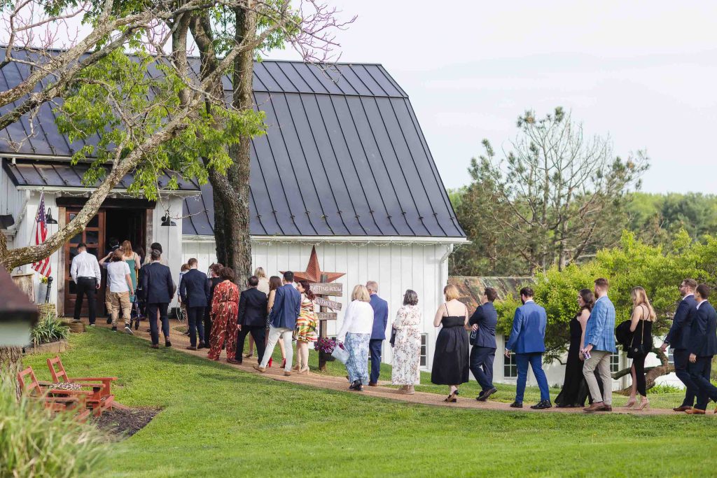 A candid group preparing for a wedding outside of a barn.
