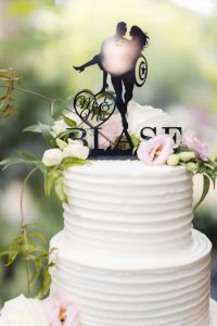 A wedding cake topper with a silhouette of a couple riding a horse.