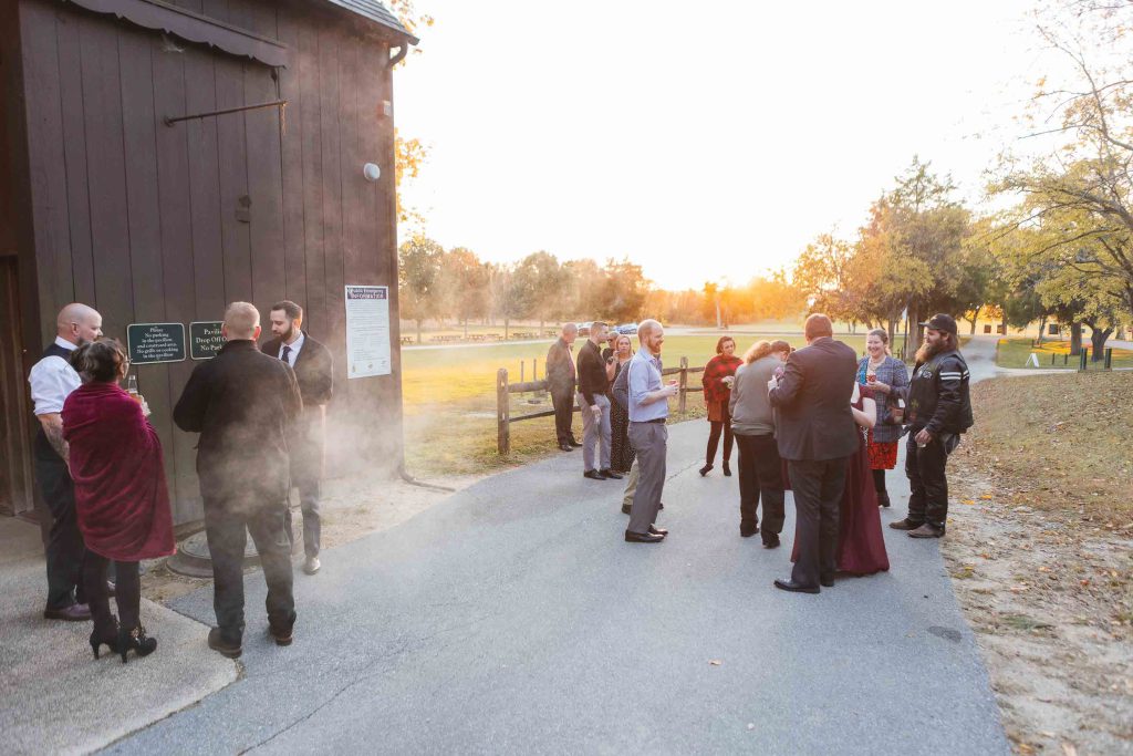 A group of people celebrating at a wedding reception in front of a barn.