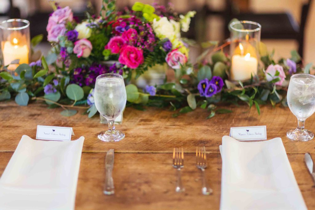 A wedding table setting with flowers and candles on a wooden table, highlighting the intricate details.