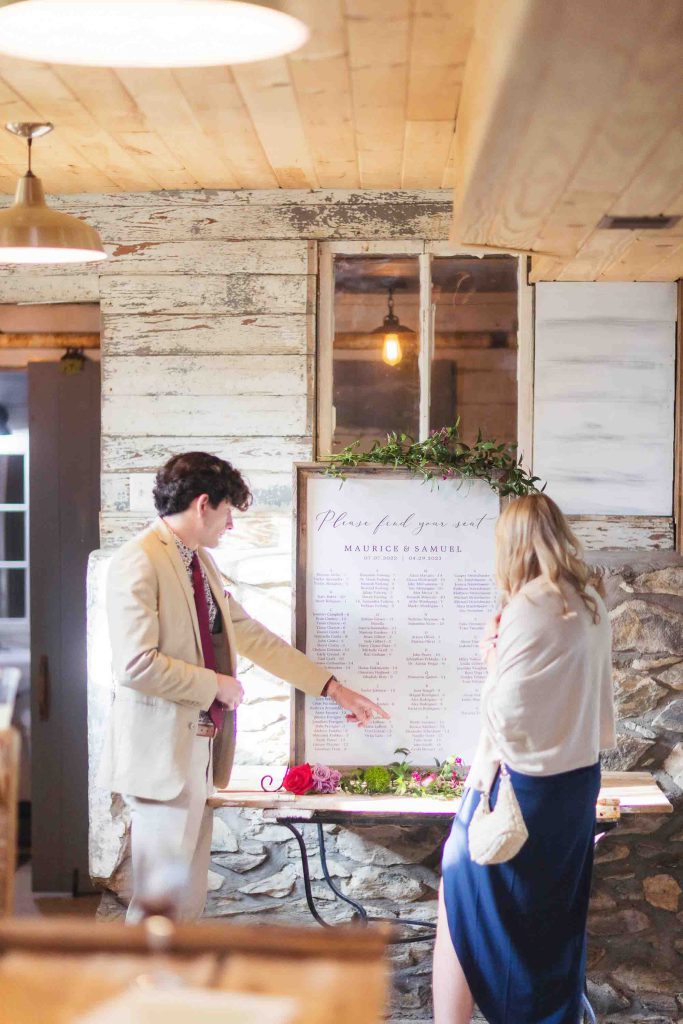 A candid couple preparing for their wedding next to a table with a sign.
