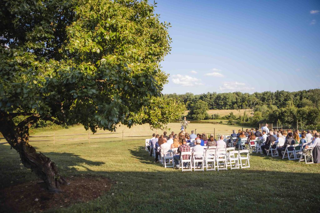 A wedding ceremony in a field surrounded by trees.