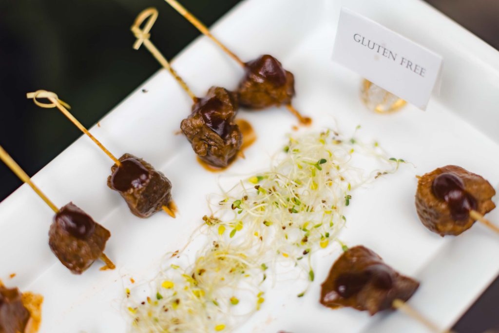 Skewers of meat on a white plate showcasing intricate details.