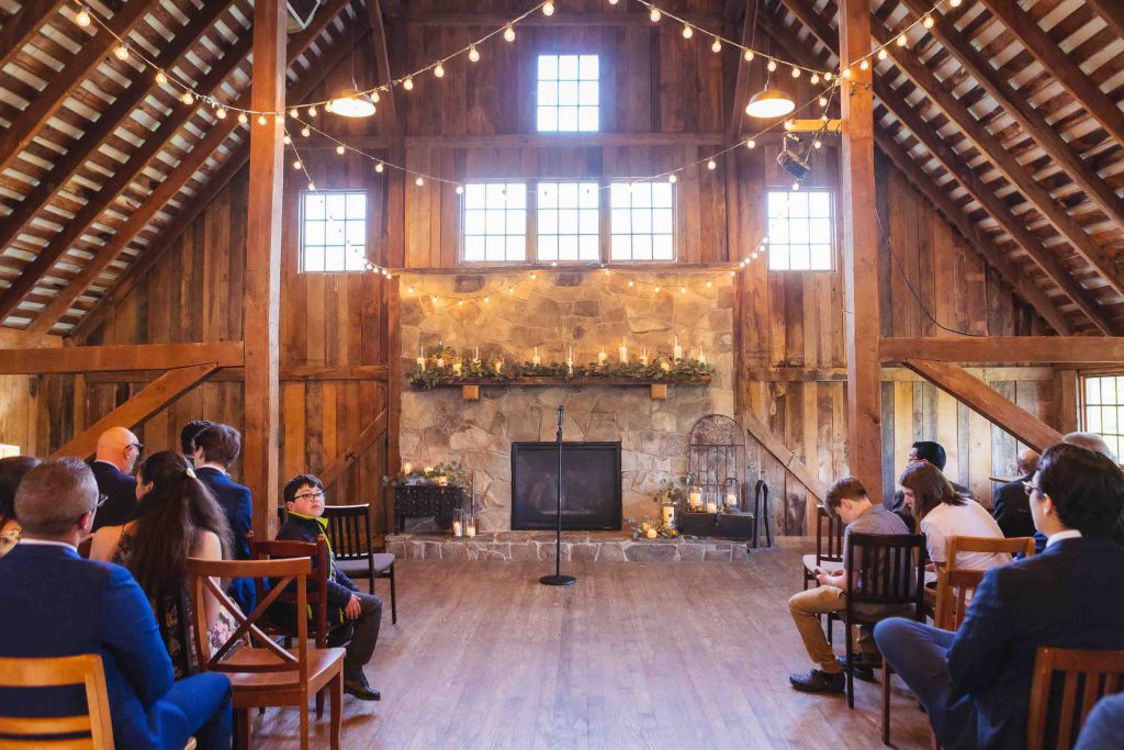A wedding ceremony with string lights in a barn.