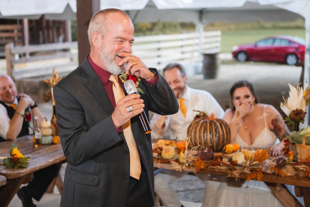 A man speaking into a microphone at a wedding reception.