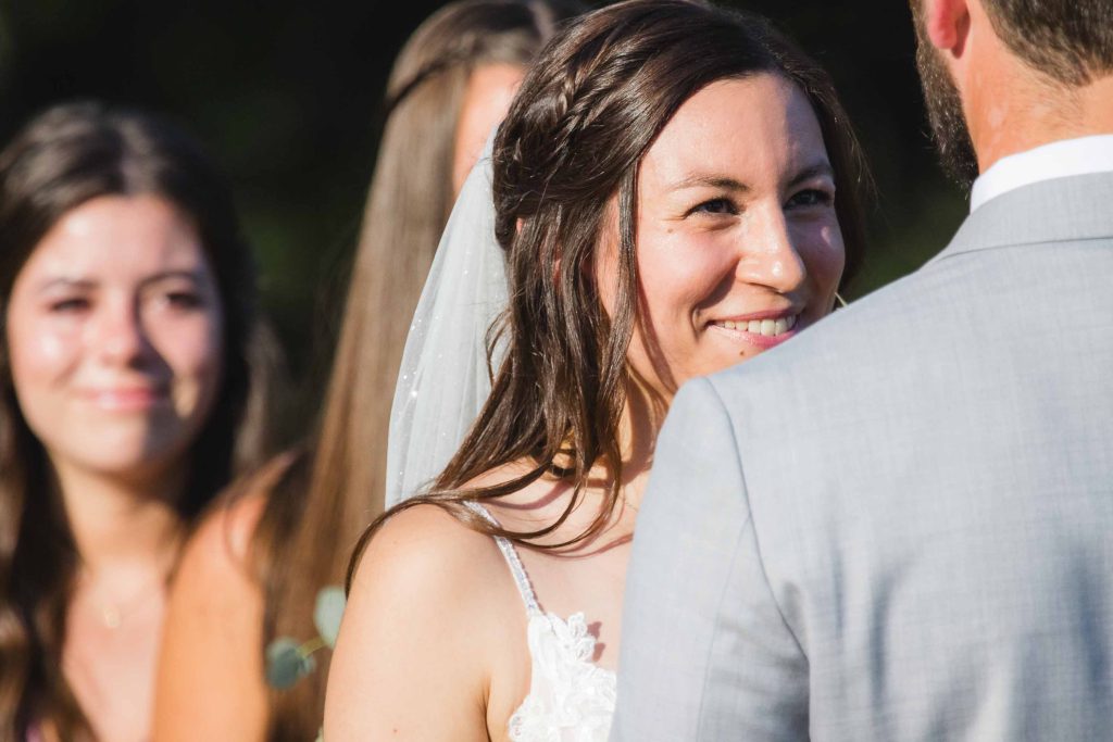 A bride and groom smile at each other during their wedding ceremony.