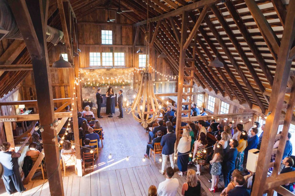 A barn wedding ceremony with a large crowd.