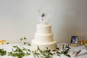 A detailed white wedding cake with two figurines on top.