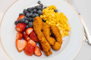 A plate with chicken, strawberries and blueberries served at a wedding.