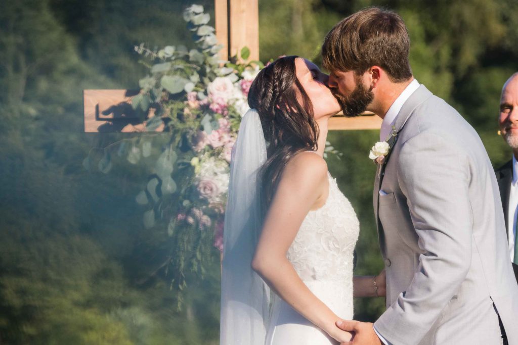 A couple shares a passionate kiss during their wedding ceremony.