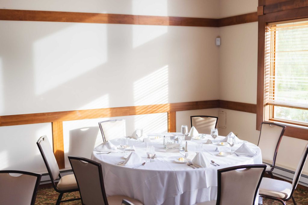A wedding reception with a detailed table and chairs set up.