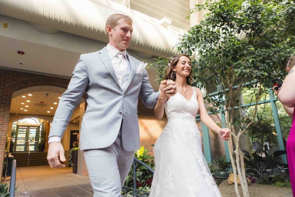 A bride and groom walking through a wedding reception.
