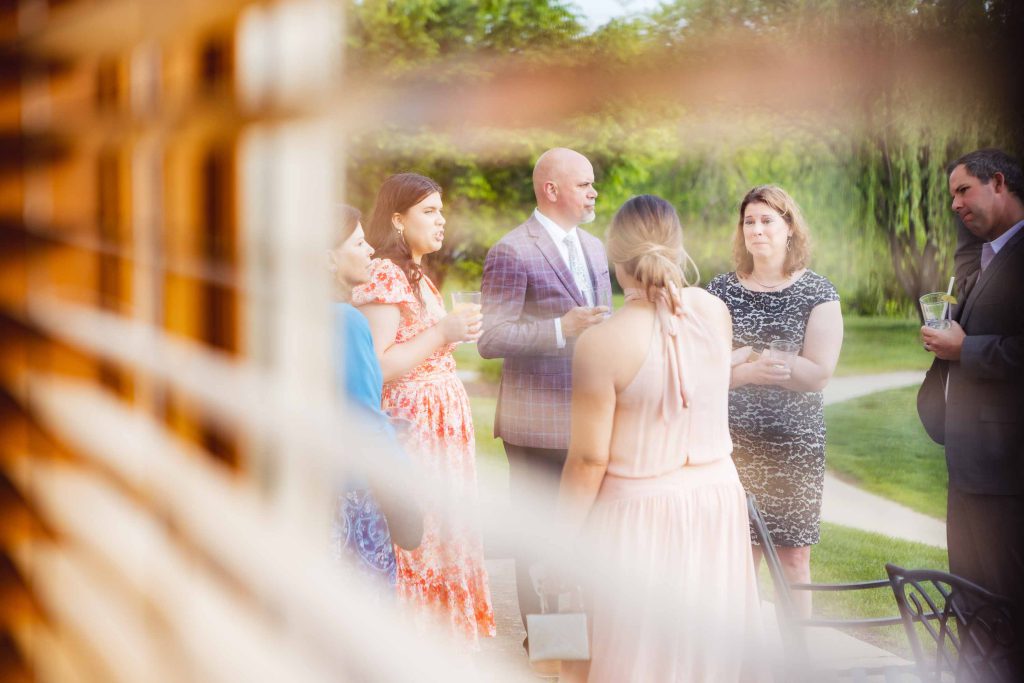 A candid wedding preparation moment captured with a group of people standing in front of a window.